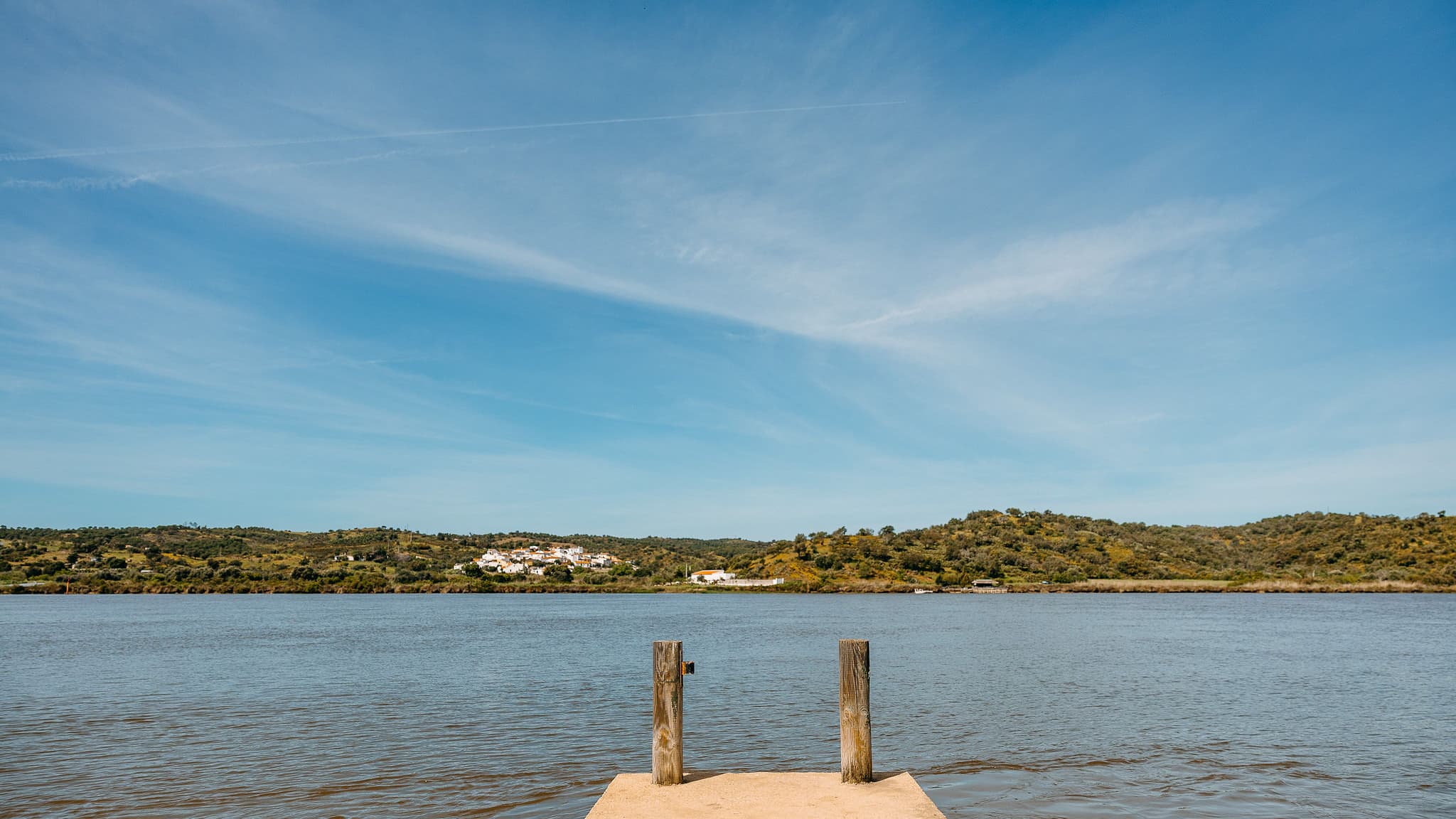 El embarcadero de madera de la finca entrando en el Guadiana, con el río ancho y las lomas de la orilla portuguesa al fondo