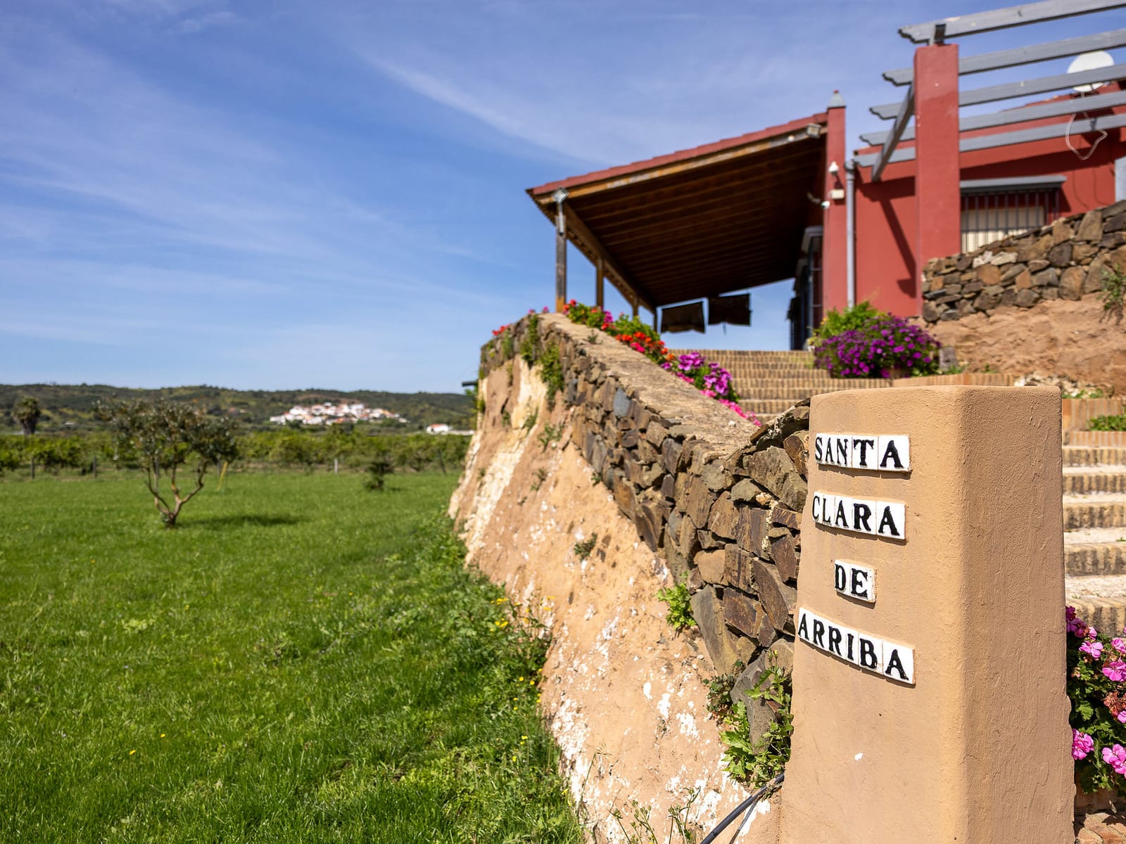 El rótulo de azulejo de la entrada de la finca, con el nombre «Santa Clara de Arriba», junto al murete de piedra