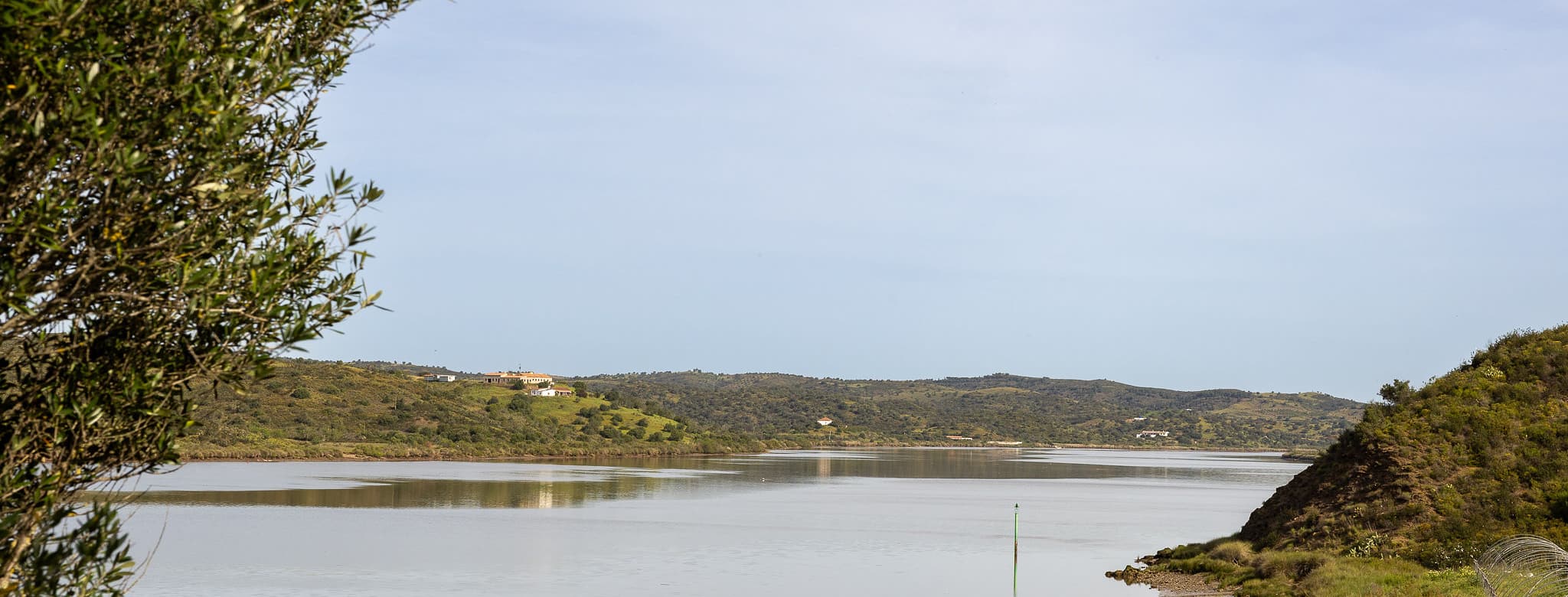 El Guadiana abriéndose hacia la desembocadura, con el arenal de la orilla en primer plano y las lomas arboladas al fondo