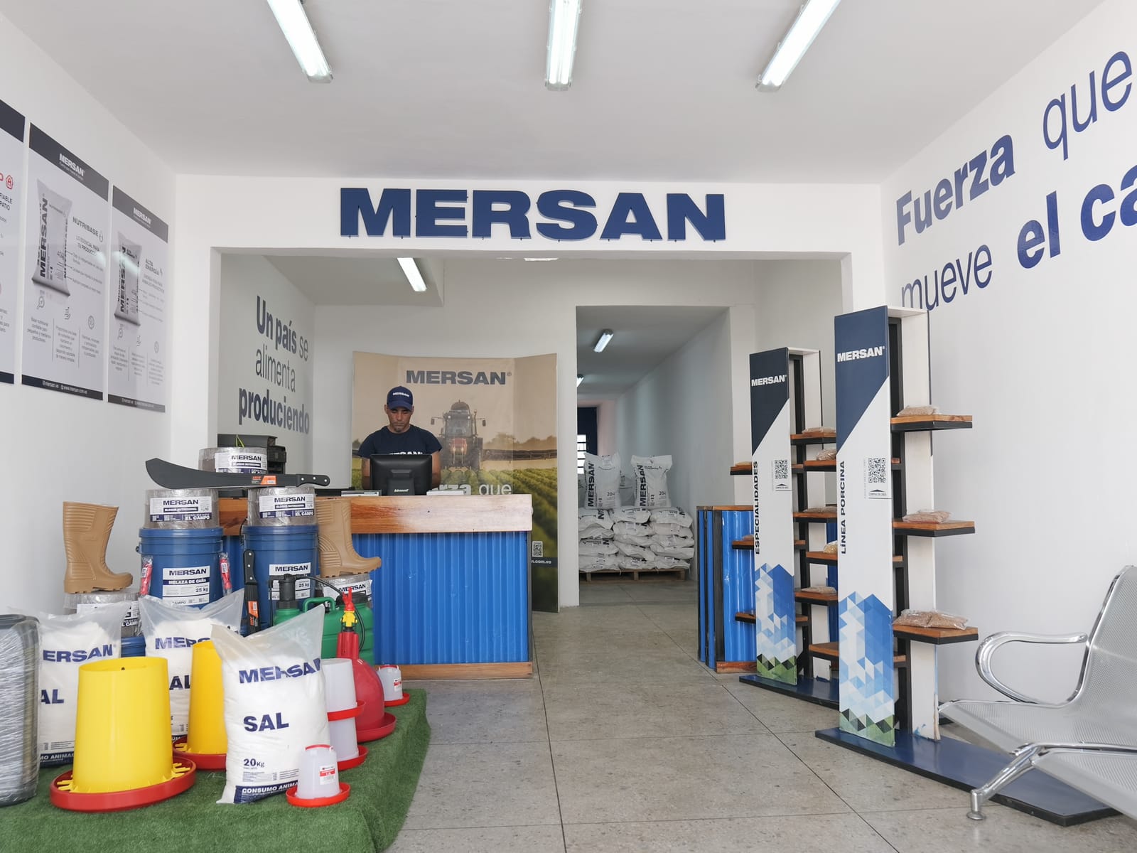 Interior de una tienda Mersan con el mostrador de atención, producto en exhibición y el lema «Fuerza que mueve el campo» pintado en la pared