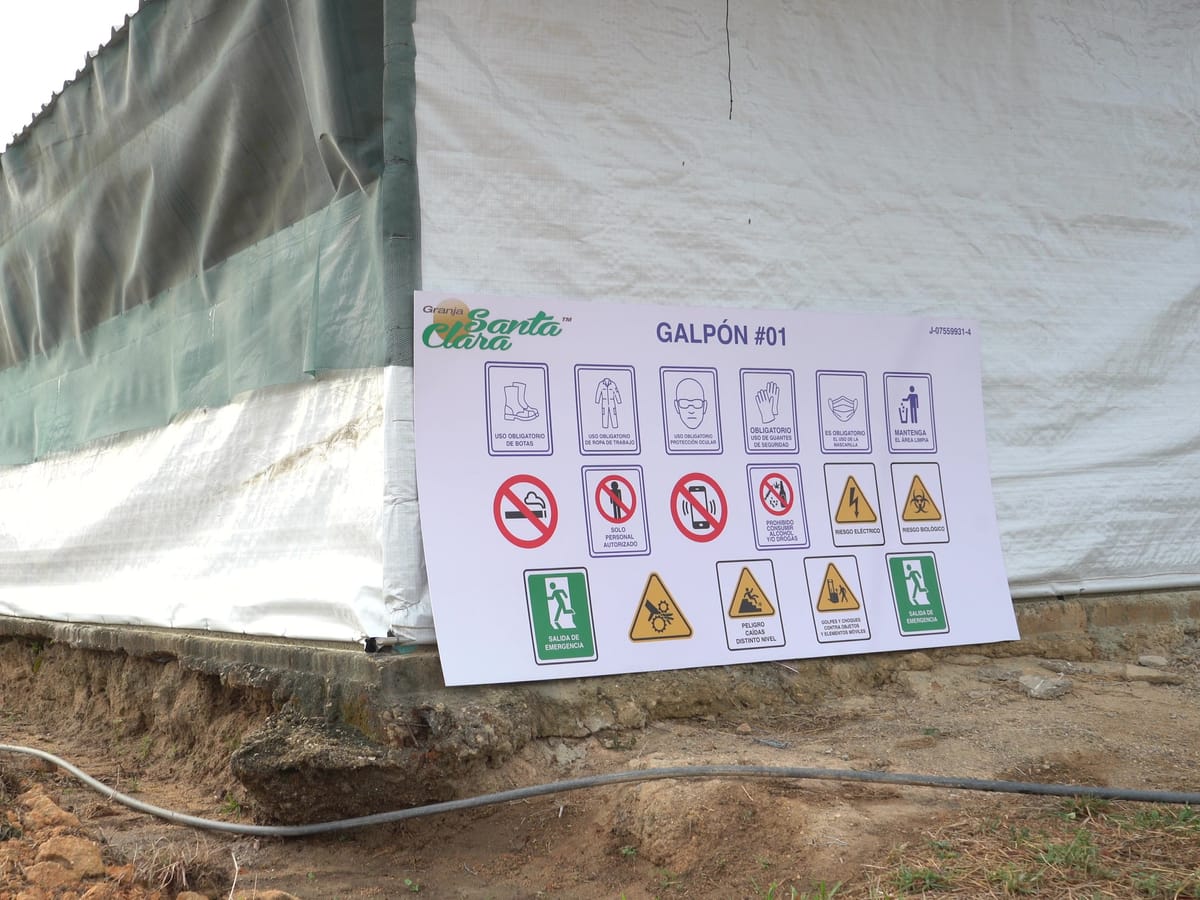 Cartel de bioseguridad del galpón 01 en la pared exterior, con la señalización de acceso obligatorio y restringido